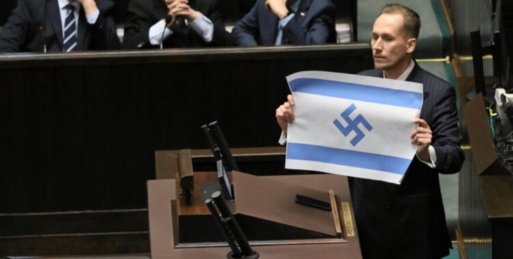 برلماني بولندي يرفع علم إسرائيل يحمل رمزاً نازياً ويشبه ممارسات ⁧‫تل أبيب‬⁩ في ⁧‫غزة‬⁩ بـ"الرايخ الثالث"